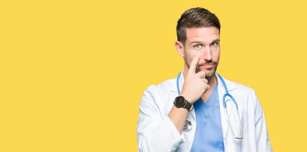 ハンサムな医者男が身に着けている医療制服上分離目見てするジェスチャーに 怪訝な表情のポインティングを背景します — ストック写真