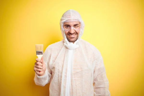 Jovem Vestindo Equipamento Pintor Segurando Pincel Pintura Sobre Fundo Amarelo — Fotografia de Stock