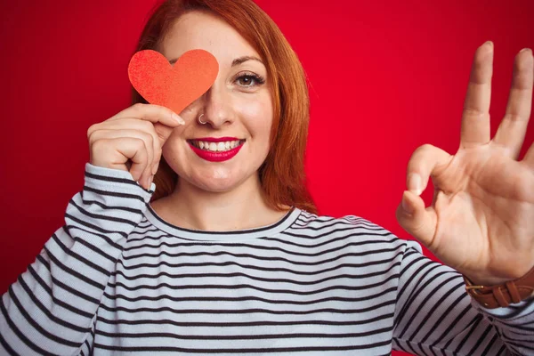 Giovane Rossa Donna Romantica Tenendo Cuore Sfondo Rosso Isolato Facendo — Foto Stock