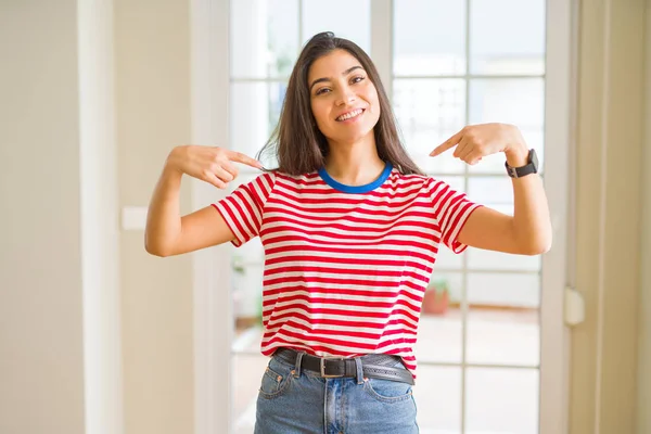 顔に笑顔で自信を持っているカジュアルなTシャツを着て若い美しい女性 誇りと幸せ指で自分自身を指して — ストック写真