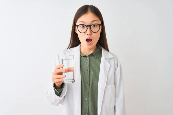 孤立した白い背景の上に水を飲むメガネをかけた若い中国のドゥークター女性は 驚きの顔でショックを受け 恐怖と恐怖表現で興奮 — ストック写真