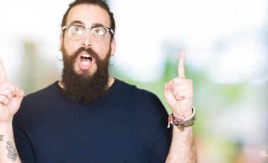 Uzun saç ve sakal gözlüklü genç hipster adamla hayret ve yukarıya bakıp parmakları ile işaret şaşırttı ve silah kaldırdı.