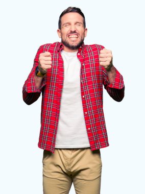 Rahat gömlek giyen yakışıklı adam gülümseyerek zafer kutlayan kaldırdı kolları ile başarı için heyecanlı. Kazanan kavramı.