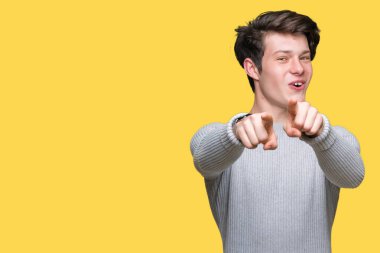 Genç yakışıklı adam giyen kış kazak izole üzerinde arka plan size işaret ve parmaklar, olumlu ve neşeli gülümseyen kamerayla