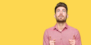 Genç yakışıklı iş casual adam hayret ve yukarıya bakıp parmakları ile işaret şaşırttı ve silah kaldırdı.