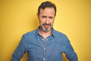 Izole sarı arka plan üzerinde gri saçlı yakışıklı orta yaş yaşlı adam depresif ve sıkıntı için endişe, kızgın ve korkmuş ağlıyor. Hüzünlü ifade.
