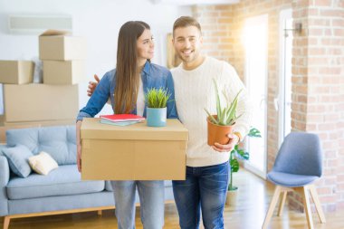 Güzel genç çift yeni bir ev, yeni bir dairede mutlu tutan karton kutular gülümseyen hareket