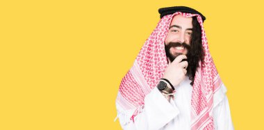 Arap iş adamı uzun saçlı geleneksel keffiyeh giyiyor emin çapraz kolları olan gülümseme ile kameraya bakarak eşarp ve üzerinde yükseltilmiş çene el. Pozitif düşünce.