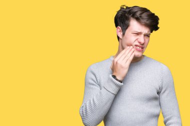 Diş ağrısı veya dişlerde dişlerle ilgili hastalık nedeniyle ağız acı ifadesi ile el ile dokunmak izole arka plan üzerinde kış kazak giyen genç yakışıklı adam. Diş hekimi kavramı.