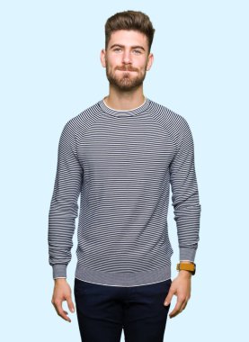 Yakışıklı delikanlı giyen kazak şişirme yanakları komik surat ile çizgili. Ağız ile hava, deli ifade şişirilmiş.