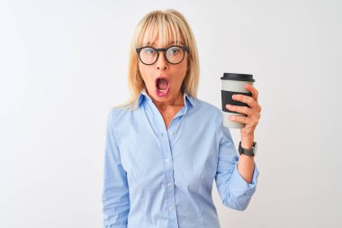 Izole beyaz arka plan üzerinde kahve içen gözlük takan orta yaş iş kadını sürpriz bir yüz ile şok korkmuş, korku ve korku ifade ile heyecanlı