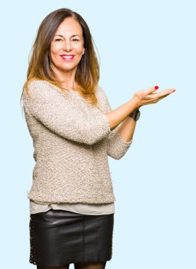 Moda kazak giyen güzel orta yaş kadın el ve reklam mutlu ve kendinden emin gülümseyen sunulması avuç, yanında işaret