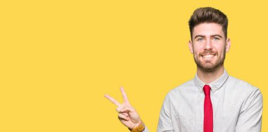 Mutlu yüz zafer işareti yaparken kameraya göz kırpıyor ile gülümseyen genç yakışıklı iş adamı. İki numaralı.