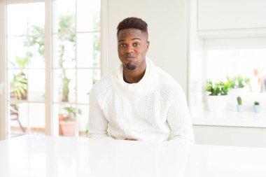 Beyaz masadaki yakışıklı afro-amerikan adam, komik suratlı yanakları şişiriyor. Ağız hava ile şişirilmiş, deli ifade.