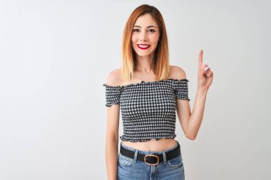 Rahat beyaz arka plan üzerinde duran rahat t-shirt giyen güzel kızıl saçlı kadın gösteren ve kendinden emin ve mutlu gülümserken parmak sayısı bir işaret.