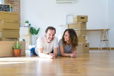 Orta yaş Senior romantik çift yerde yatıyor, yeni bir eve hareket için mutlu gülümseyen, rahatlatıcı ve ambalaj kutularının bir mola alarak