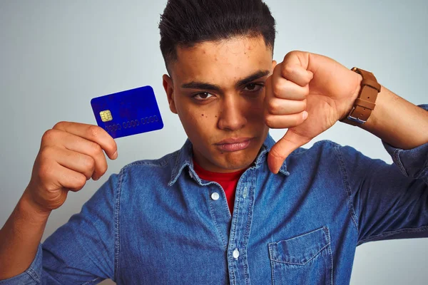 年轻的巴西客户男子拿着信用卡站在孤立的白色背景与愤怒的脸 负面标志显示不喜欢与拇指向下 拒绝概念 — 图库照片