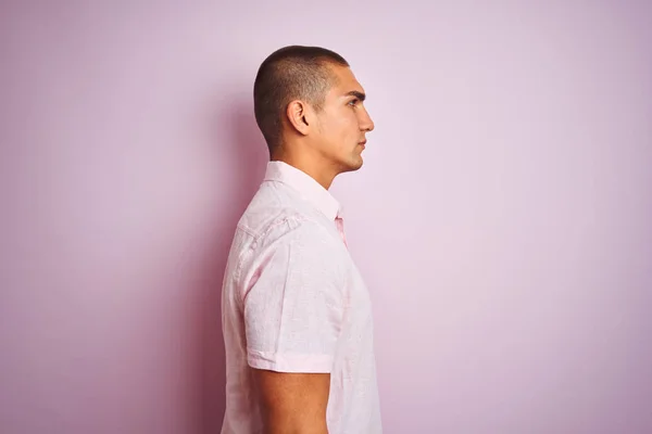 ピンクの孤立した背景の上にエレガントなシャツを着た若いハンサムな男は 自信に満ちた笑顔で自然な顔でプロフィールポーズをリラックス — ストック写真