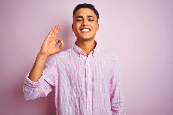 분홍색 서있는 셔츠를 브라질 남자가 손가락으로 사인을하고 긍정적 미소를 있습니다 — 스톡 사진