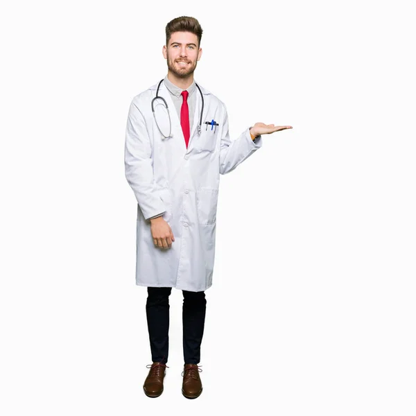 Jonge Knappe Dokter Man Met Medische Vacht Lacht Vrolijk Presenteren — Stockfoto