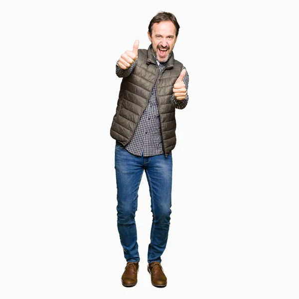 冬のベストを着た中年のハンサムな男は 手で肯定的なジェスチャーを行うことを承認し 笑顔で成功のために幸せ カメラを見て 勝者のジェスチャー — ストック写真