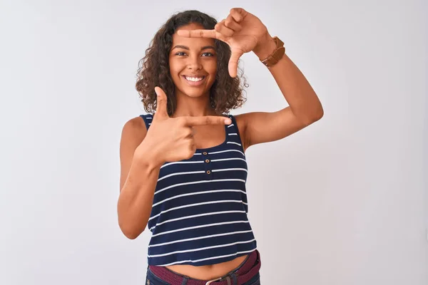 孤立した白い背景の上に立つストライプのTシャツを着た若いブラジル人女性は 幸せそうな顔で手と指でフレームを作って微笑んでいます 創造性と写真のコンセプト — ストック写真