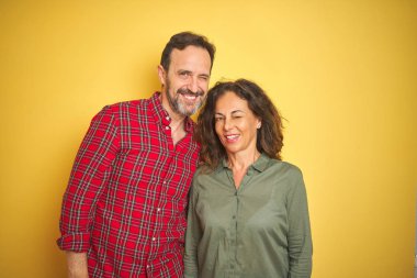 Izole sarı arka plan üzerinde Güzel orta yaş çift seksi ifade, neşeli ve mutlu yüz ile kameraya bakarak göz kırpma.