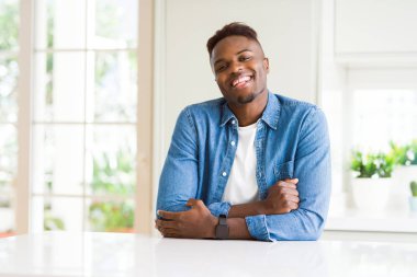 Yakışıklı afro-amerikan adam evde mutlu yüz kameraya bakarak çapraz kolları ile gülümseyerek. Pozitif kişi.