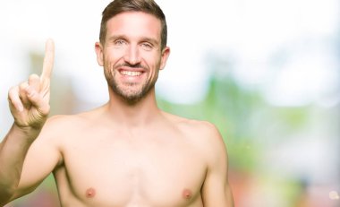 Yakışıklı gömleksiz adam gösteren çıplak göğüs gösterme ve işaret yukarıya ile parmak sayı bir süre gülümseyen emin ve mutlu.
