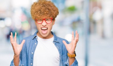 Yakışıklı genç afro saçlı gözlüklü çılgın ve deli bağırarak ve agresif ifade ve silah kaldırdı bağırıyor. Hayal kırıklığı kavramı.