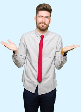 Genç yakışıklı iş adam clueless ve şaşkın bir ifadeyle kollar ve eller kaldırdı. Şüphe kavramı.