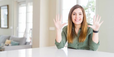 Evde gösteren ve parmakları ile işaret eden güzel genç kadın emin ve mutlu gülümserken on numara.