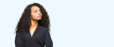 Kıvırcık saçlı Genç güzel kız şık elbise giymiş görünümlü yan ve bakıyor uzağa düşünme gülümseyen.