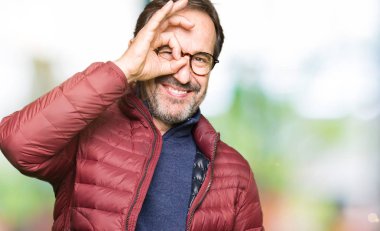 Gözlük ve kış ceket giyen orta yaş yakışıklı adam el gülümseyen ok jest yapıyor, göz mutlu yüz ile parmaklar görünümlü.