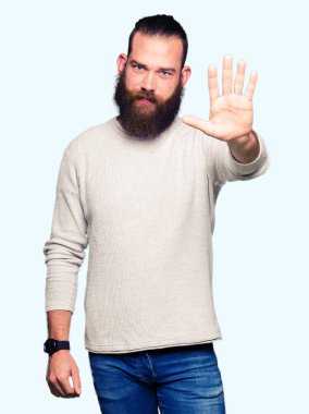 Dur yaparken rahat kazak giyen genç sarışın adam elin avuç ile şarkı. Negatif ve ciddi bir jest yüz ifadesiyle uyarı.