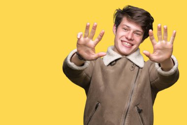 Gösterilen arka plan üzerinde kış ceket giyen genç yakışıklı adam izole ve parmakları ile işaret numara 9 kendinden emin ve mutlu gülümseyerek süre.