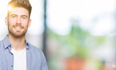 Rahat gömlek giyen genç yakışıklı sarışın adam hayran ve el ile sunmak ve parmak ile işaret ederken kameraya gülümsüyor.