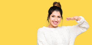 Kış kazak ile büyük ve büyük boy işaret, ölçü birimi sembol gösteren el eller giyen genç güzel kadın. Kameraya bakarak gülümsüyordu. Ölçüm kavramı.