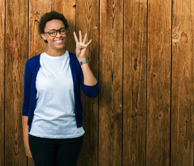 Genç güzel Afrikalı-Amerikalı kadın gözlük gösterilen ve parmakları ile işaret izole arka plan üzerinde dört kendinden emin ve mutlu gülümseyerek iken numara.