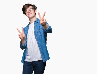 Zafer işareti yapıyor parmak gösterilen kamera seyir gülümseyen izole arka plan üzerinde gözlük takan yakışıklı delikanlı. İki numaralı.