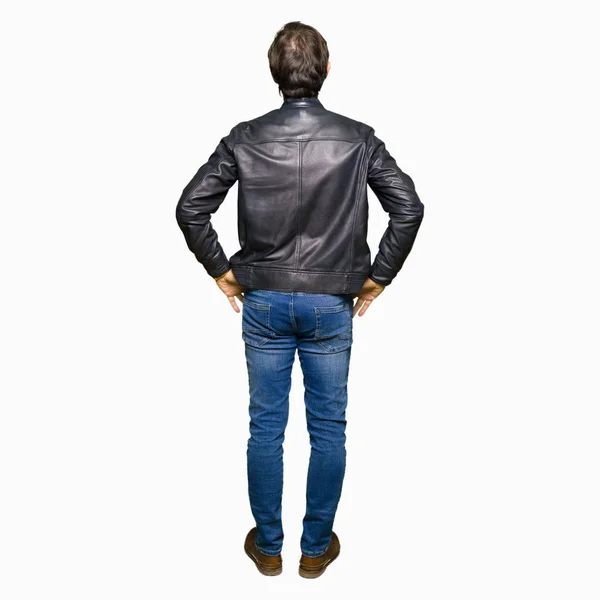 黒い革のジャケットを着た中年のハンサムな男は 体に腕を持って後ろ向きに立っている — ストック写真