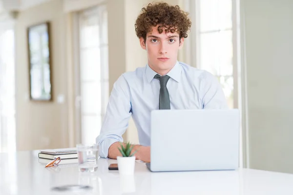 オフィスでコンピュータのラップトップで働く若いビジネスマンは 顔に真剣な表情でリラックスしました カメラを見てシンプルで自然な — ストック写真