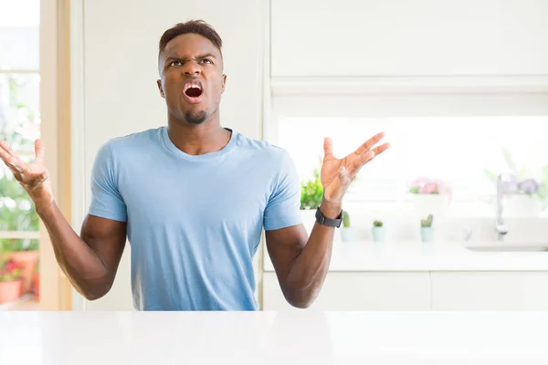 自宅でカジュアルなTシャツを着ているハンサムなアフリカ系アメリカ人男性は 攻撃的な表情と腕を上げて怒鳴り 叫びました 欲求不満の概念 — ストック写真