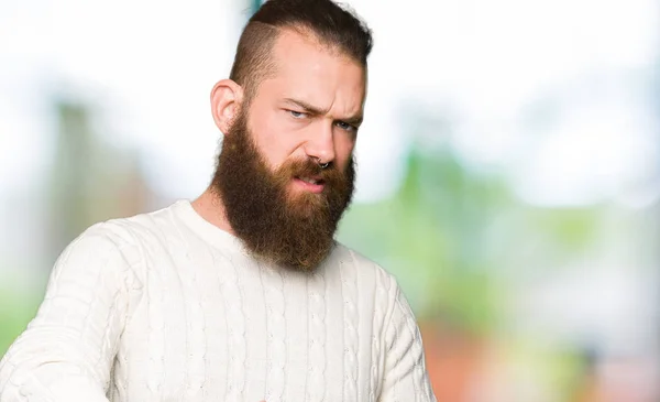 Young hipster man wearing winter sweater disgusted expression, displeased and fearful doing disgust face because aversion reaction. With hands raised. Annoying concept.