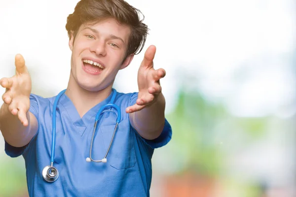 若い医師は 抱擁のために開いた腕で微笑んでカメラを見て 孤立した背景の上に医療の制服を着て 幸せを抱く陽気な表情 — ストック写真