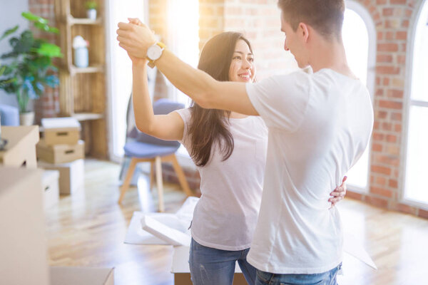 Young beautiful couple dancing at new home around cardboard boxes