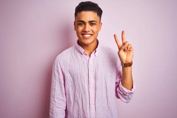 孤立したピンクの背景の上に立つシャツを着た若いブラジル人男性は 自信を持って幸せに微笑みながら 指ナンバー2を示し 指を上げている — ストック写真