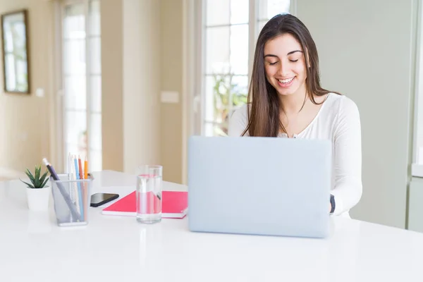 Молодая красивая женщина улыбается счастливой и работает с помощью компьютера — стоковое фото