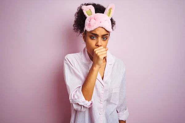 年轻的非洲裔美国妇女穿着睡衣和面具在孤立的粉红色背景感觉不舒服和咳嗽作为感冒或支气管炎的症状 医疗保健理念 — 图库照片