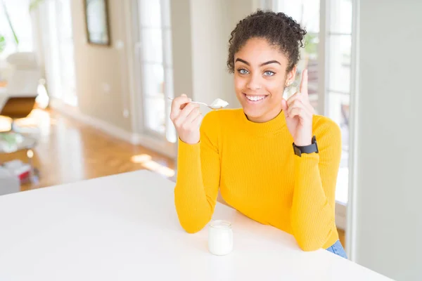 Mujer Afroamericana Joven Comiendo Yogur Natural Saludable Sorprendida Con Una —  Fotos de Stock